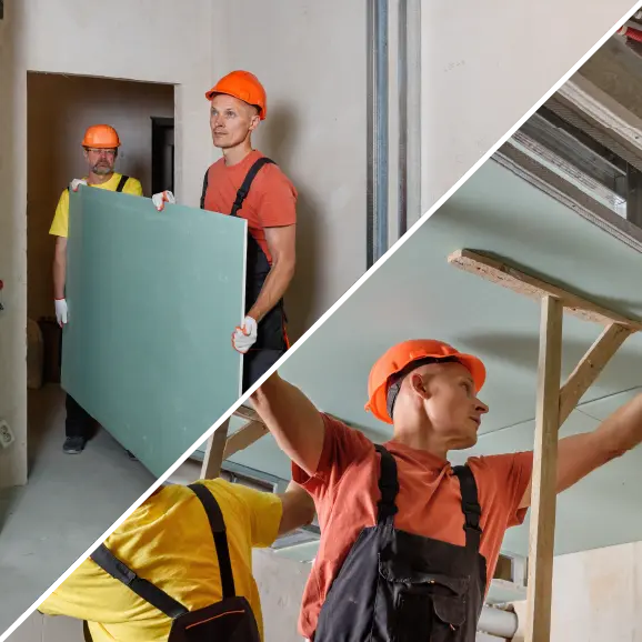 Zwei Bauarbeiter mit orangefarbenen Schutzhelmen arbeiten gemeinsam daran, Trockenbauplatten an der Decke zu bewegen und zu montieren.