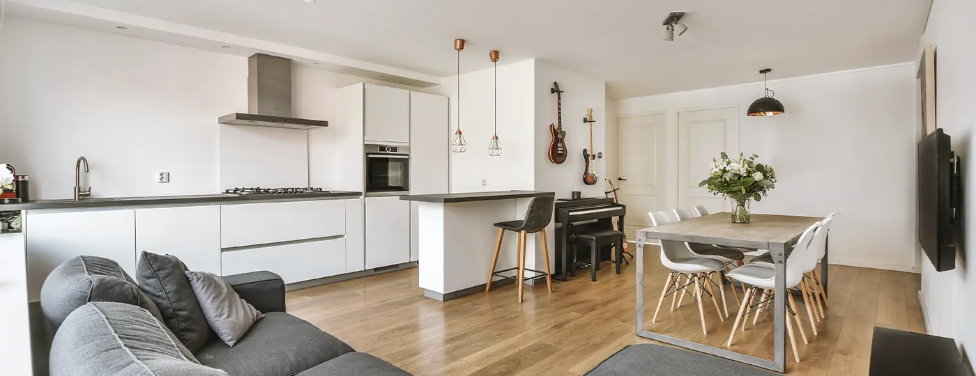 Eine moderne Wohnung mit offenem Grundriss, die Küche, Essbereich und Wohnzimmer vereint und mit Musikinstrumenten (Gitarren und einem Klavier) ausgestattet ist.