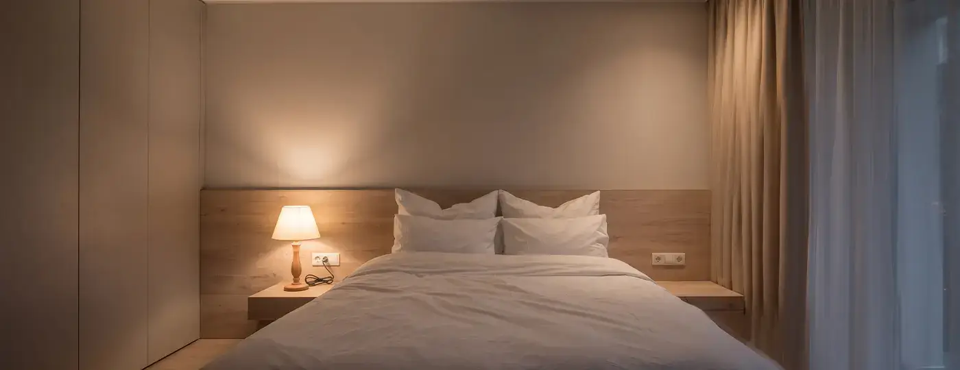 Ein gemütliches Schlafzimmer mit einem Bett und einer klassischen Nachttischlampe auf dem Nachttisch.