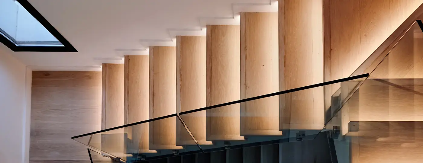 Moderne Holztreppe mit Glasgeländer und LED-Beleuchtung.