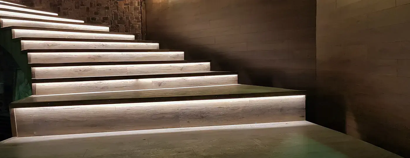 Gewendelte Holztreppe mit heller LED-Beleuchtung unter jeder Stufe.