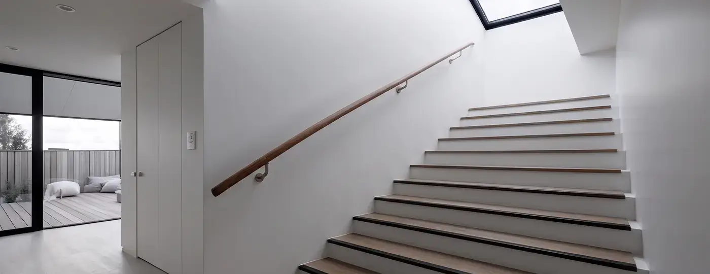 Helle, minimalistische Treppe mit Holzoberflächen an den Trittstufen und am Handlauf.