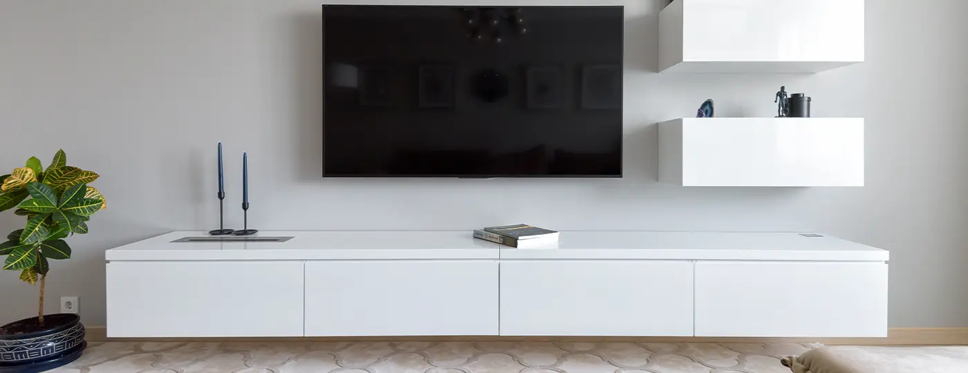 Ein modernes, weißes, wandmontiertes TV-Möbel mit Fernseher und Regalen im Wohnzimmer.