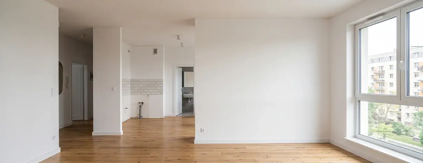 Eine leere, helle Wohnung mit weißen Wänden und einem Holzboden.