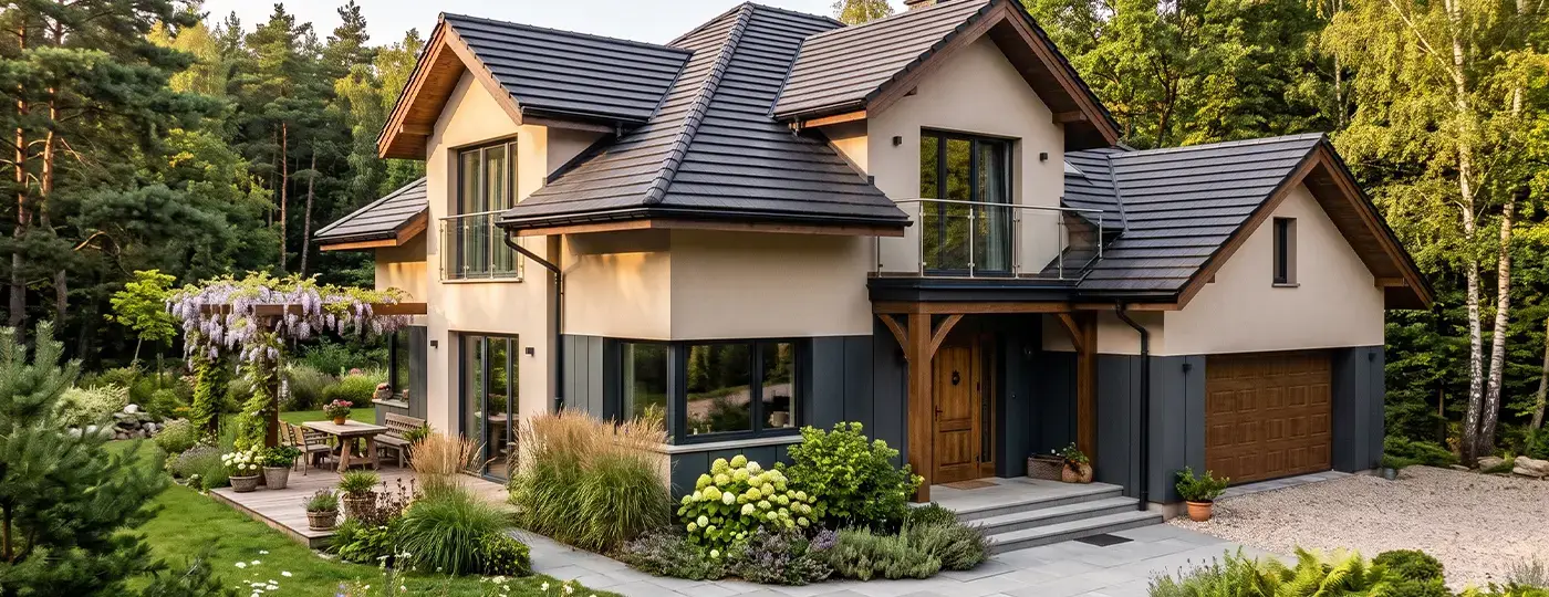 Ein elegantes zweistöckiges Haus mit dunklem Dach und heller Fassade, umgeben von einem gepflegten Garten am Waldrand.