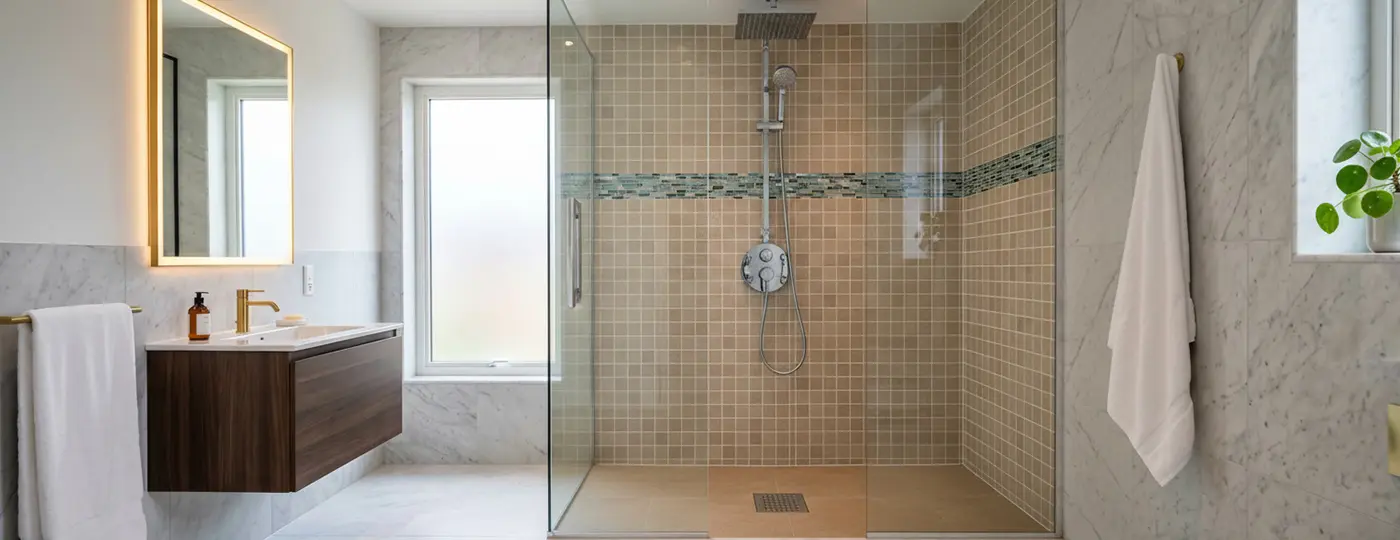 Badezimmer mit gefliester Dusche und Glasabtrennung.