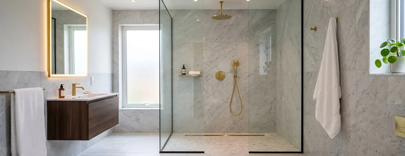 Marmorbad mit goldener Walk-in-Dusche.