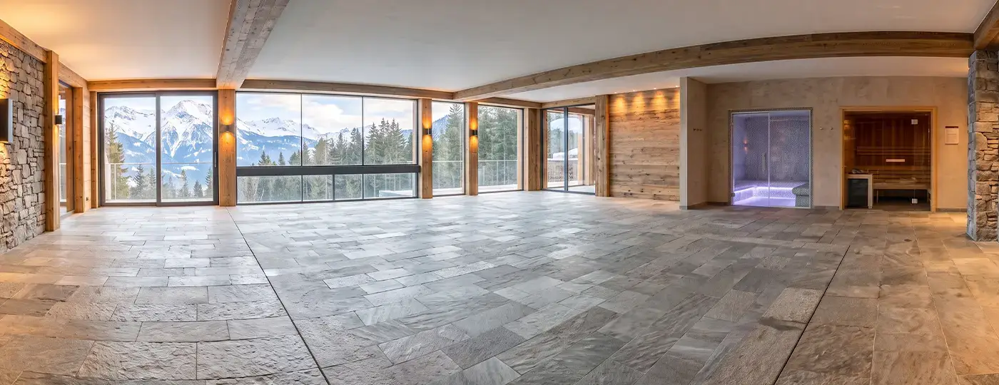 Freifläche für Pool und Wellnessbereich mit Saunen, Steinboden und Panoramablick auf die Berge