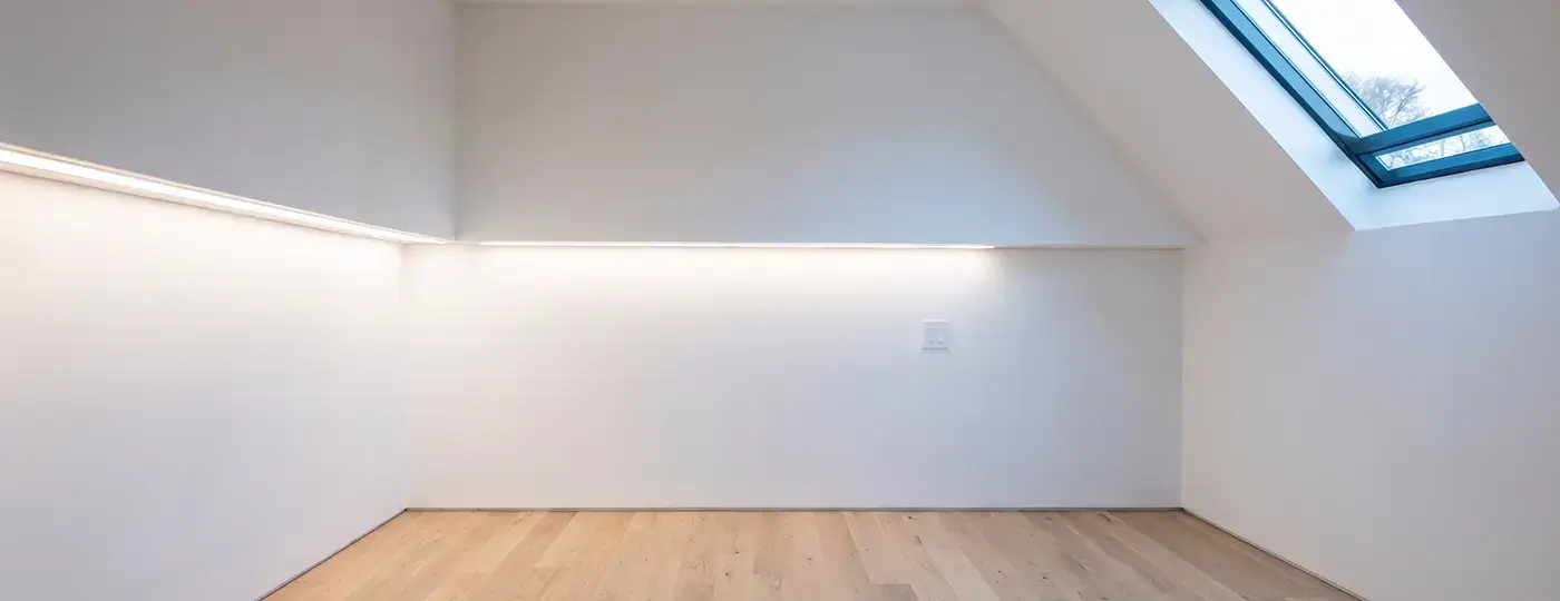 Leerer weißer Dachraum mit Dachfenster und LED-Beleuchtung.